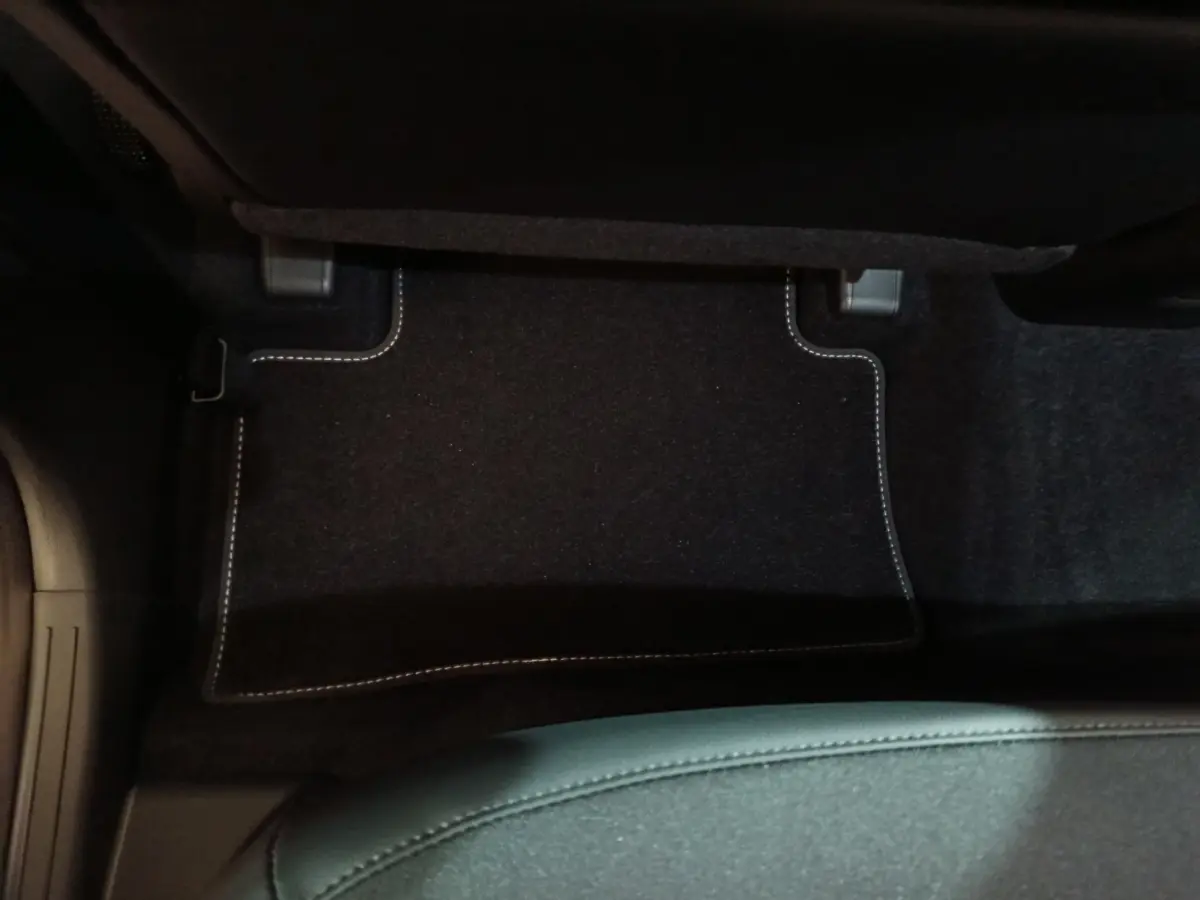 Vue plongeante sur le tapis de sol noir avec surpiqûres blanches côté passager du Hyundai Tucson gris foncé 2025.