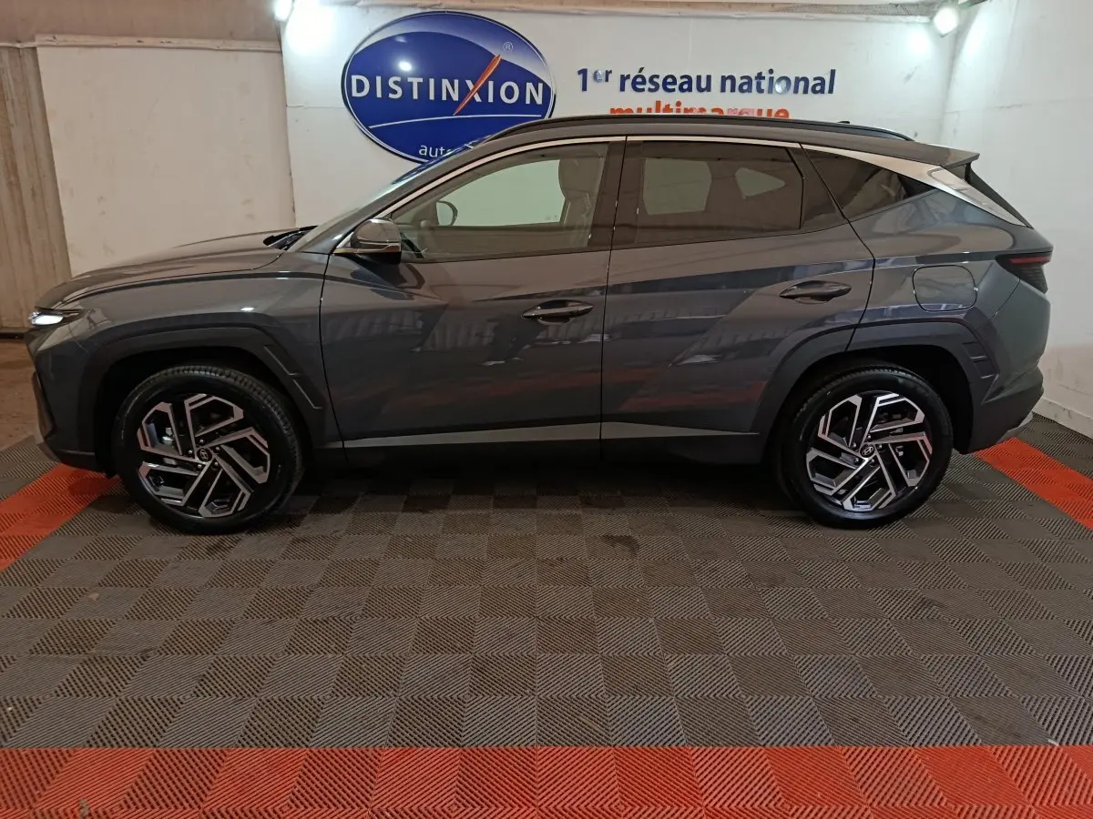 Vue de profil côté gauche d’un Hyundai Tucson gris foncé 2025 avec jantes alliage et toit noir.