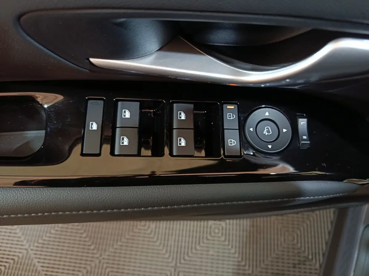 Gros plan sur les commandes de lève-vitres et rétroviseurs côté conducteur du Hyundai Tucson gris foncé 2025.
