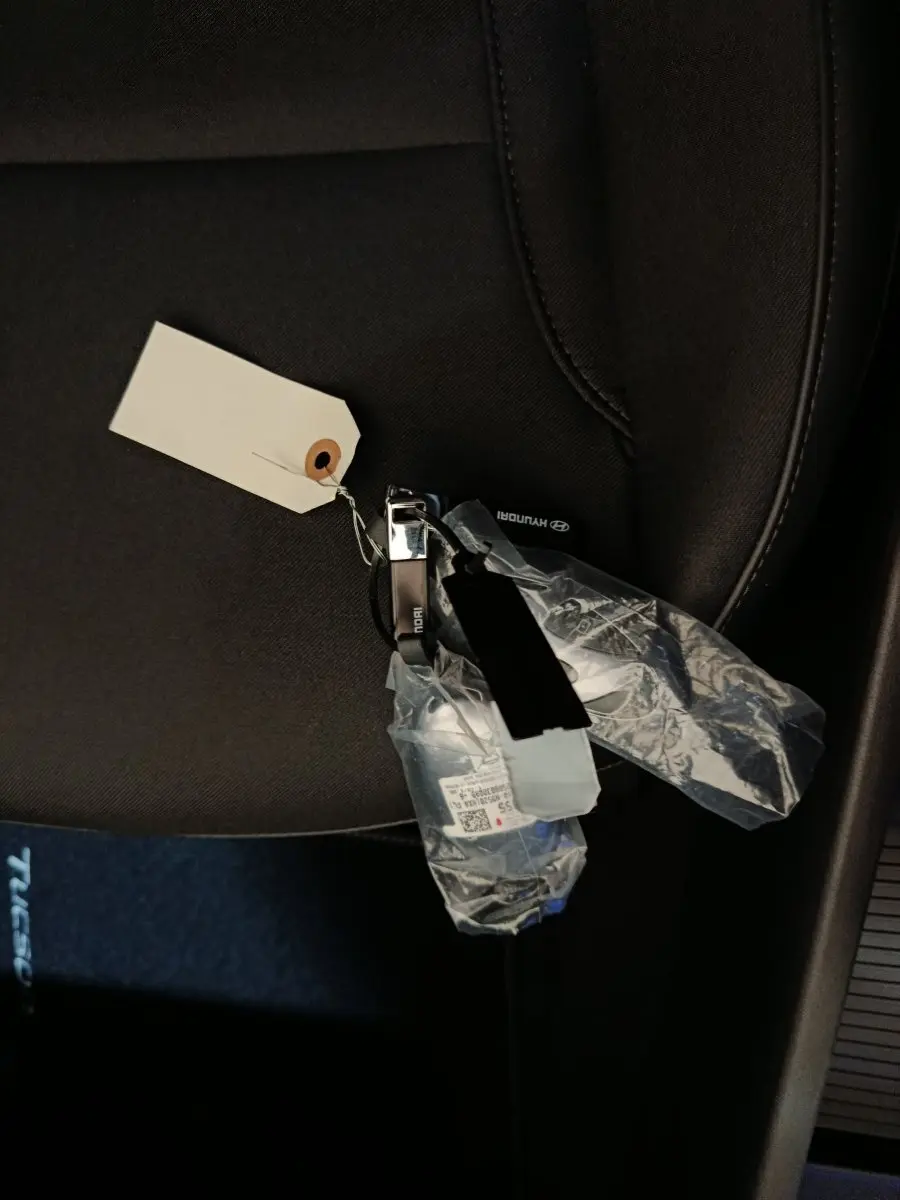 Gros plan sur la clé Hyundai posée sur un siège tissu noir à l'intérieur d'un Tucson gris foncé.