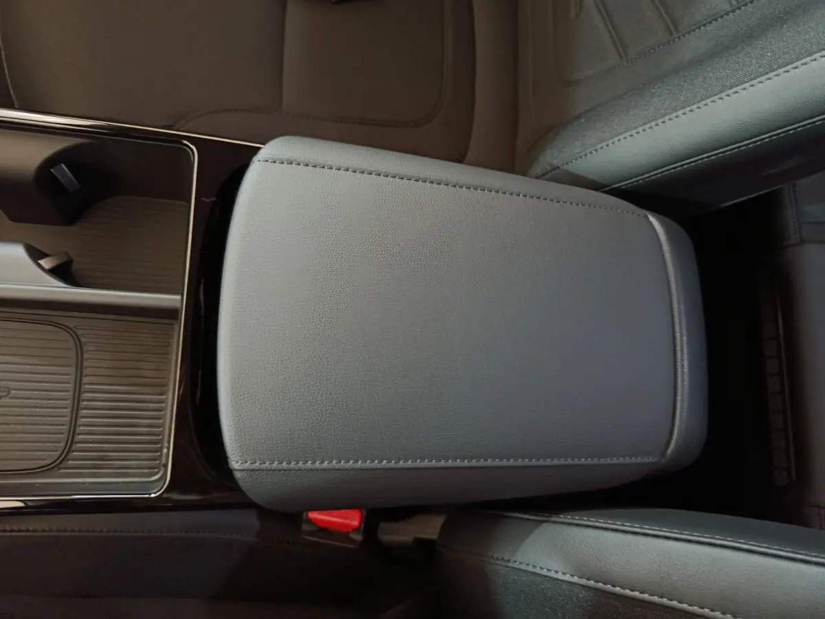 Gros plan sur l'accoudoir central en cuir gris foncé du Hyundai Tucson 2025, avec console de rangement adjacente.