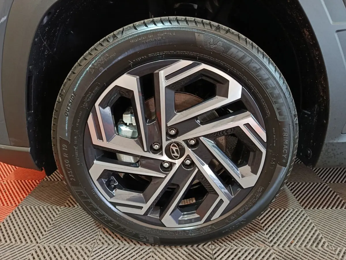 Gros plan sur la roue avant droite du Hyundai Tucson 2025 gris foncé, avec jante alliage au design géométrique moderne.