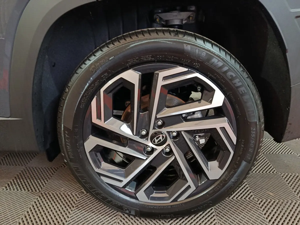 Gros plan sur la roue avant droite du Hyundai Tucson gris foncé, jante alliage au design géométrique moderne.