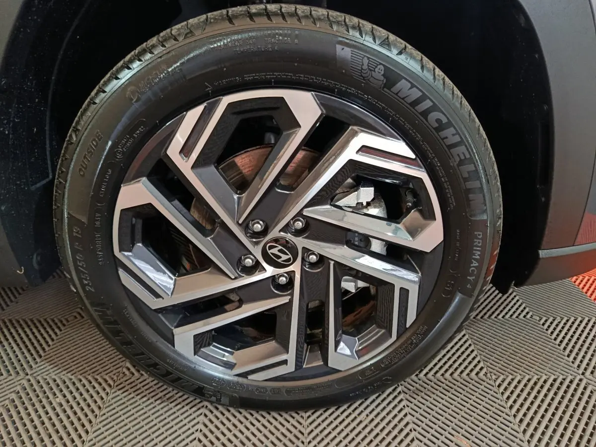 Gros plan sur la roue avant droite du Hyundai Tucson gris foncé, avec jante alliage au design géométrique.