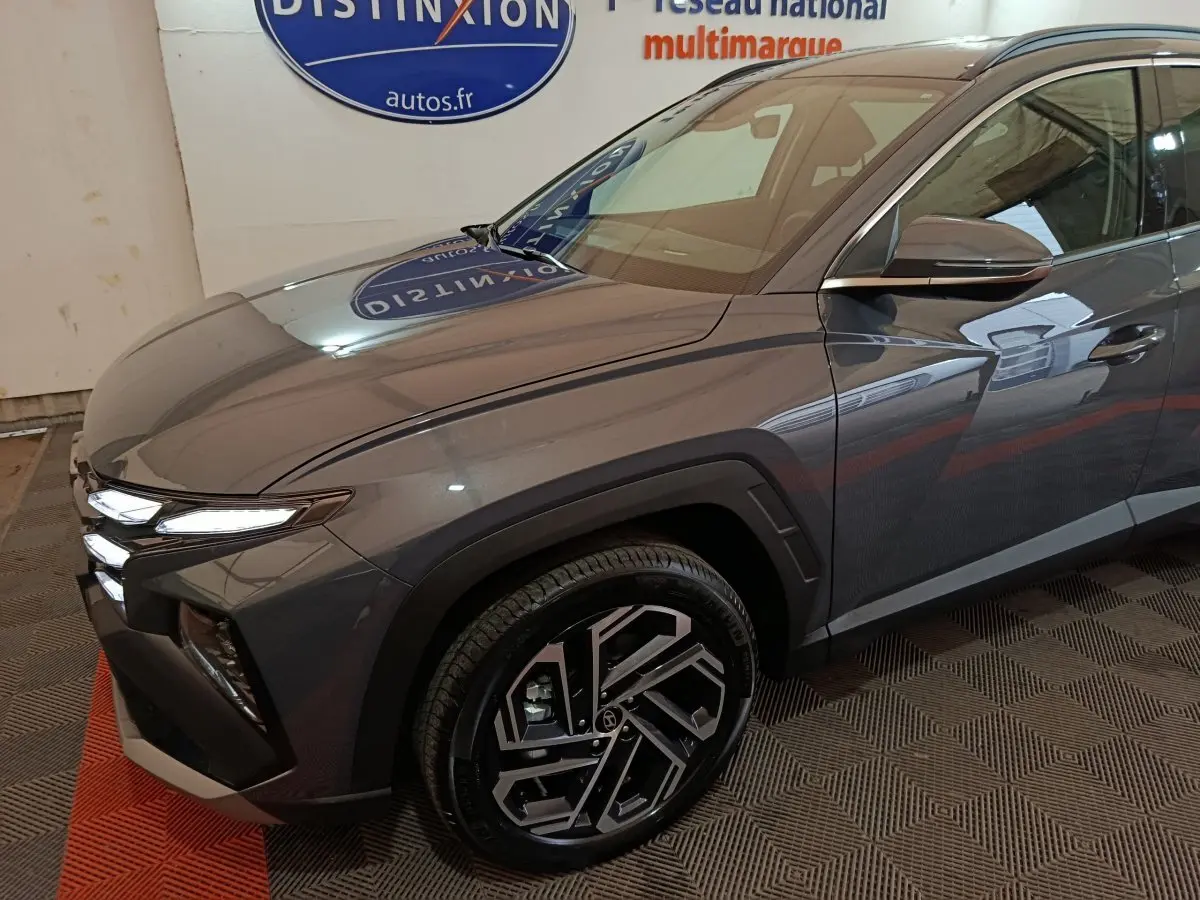 Vue 3/4 avant droit du Hyundai Tucson gris foncé avec ses phares LED et jantes alliage distinctives.