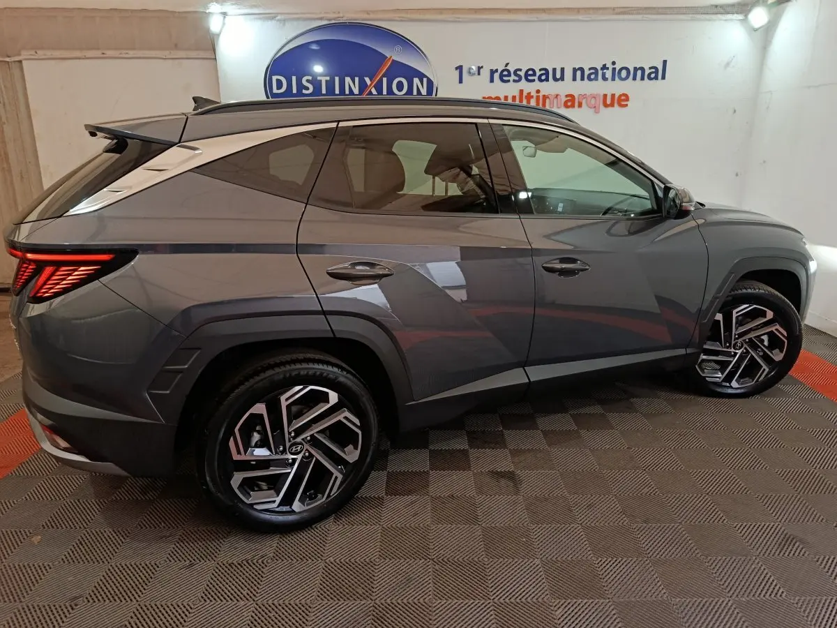 Vue latérale droite du Hyundai Tucson 1.6 Hybrid gris foncé, soulignant ses jantes alliage au design moderne et ses lignes anguleuses.