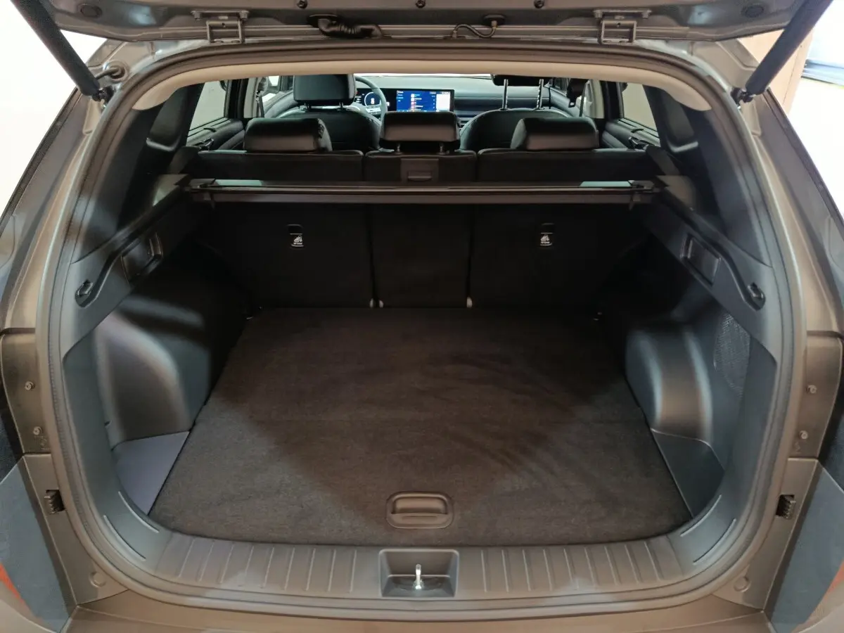 Coffre ouvert du Hyundai Tucson 2025 gris foncé, vue arrière montrant l’espace de chargement et les sièges rabattus.