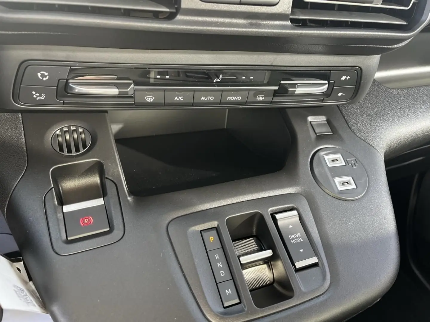 Vue rapprochée de la console centrale noire du Citroën Berlingo 2026, avec commandes climatisation et levier de boîte automatique.