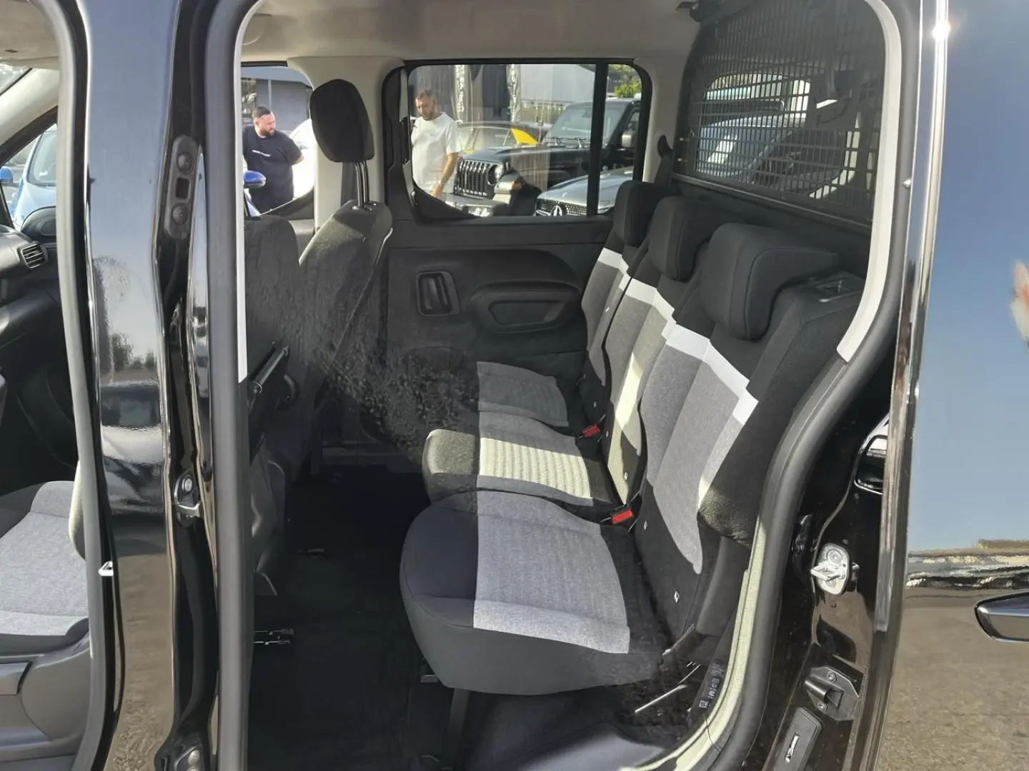 Vue intérieure côté droit du Citroën Berlingo noir Perla Nera, montrant la banquette arrière trois places en tissu bicolore.