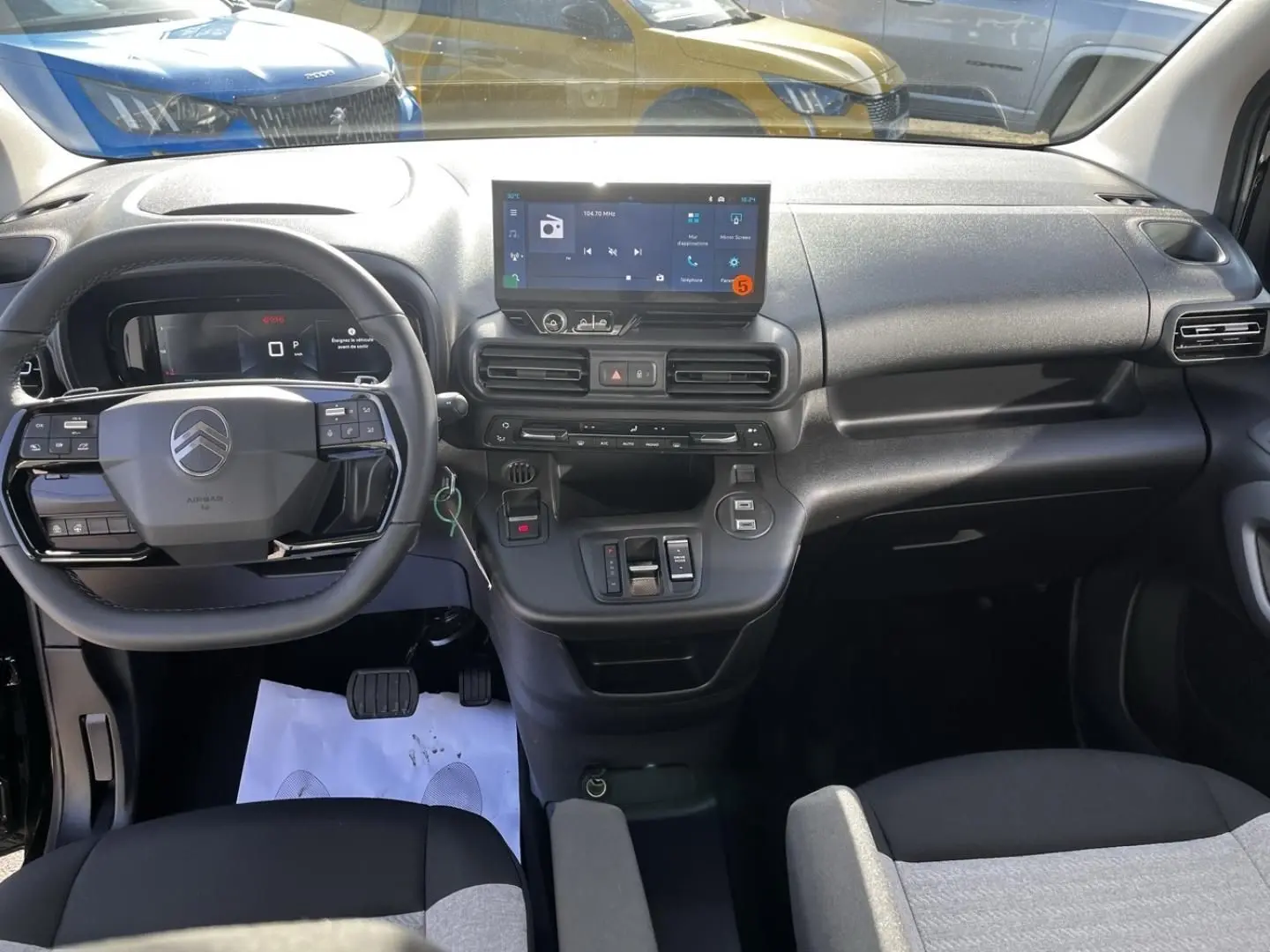 Vue intérieure frontale du tableau de bord noir et gris du Citroën Berlingo 2026 avec écran tactile et volant multifonction.