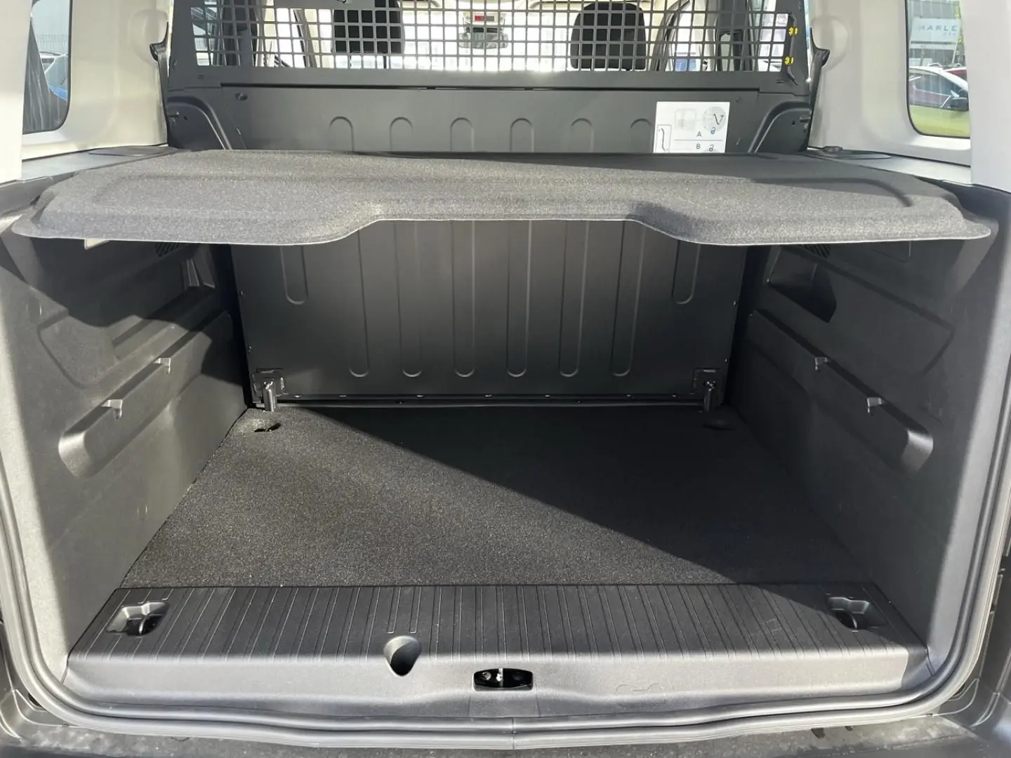 Vue arrière du coffre noir du Citroën Berlingo MPV N1 2026 avec séparation métallique et tablette de rangement.
