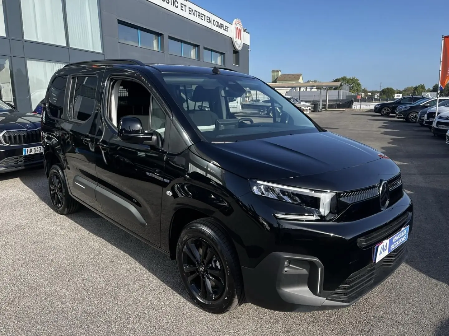 Vue 3/4 avant droite d’un Citroën Berlingo noir Perla Nera métallisé avec jantes noires et calandre moderne.