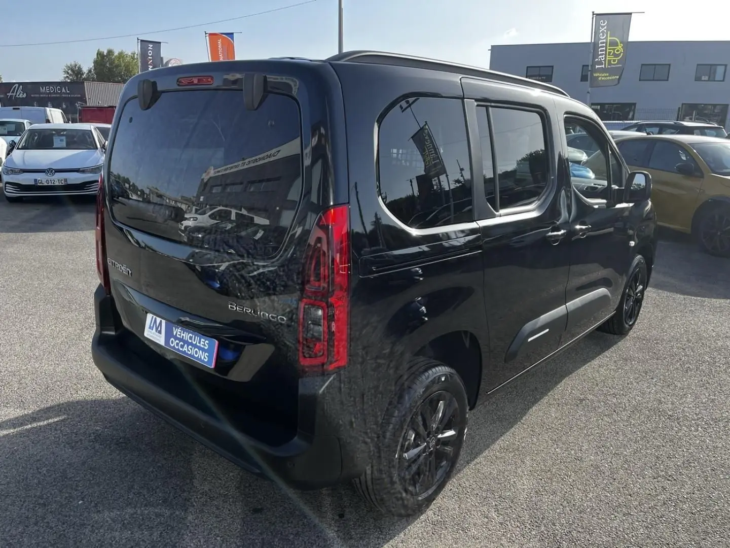 Vue 3/4 arrière droite d'un Citroën Berlingo noir Perla Nera métallisé avec vitres teintées et feux arrière LED.