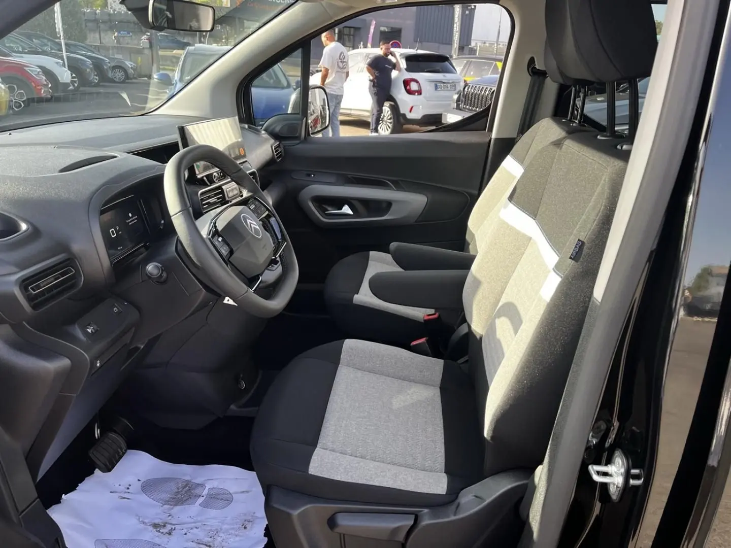 Vue intérieure côté conducteur du Citroën Berlingo noir Perla Nera, montrant les sièges tissu bicolore et le tableau de bord moderne.