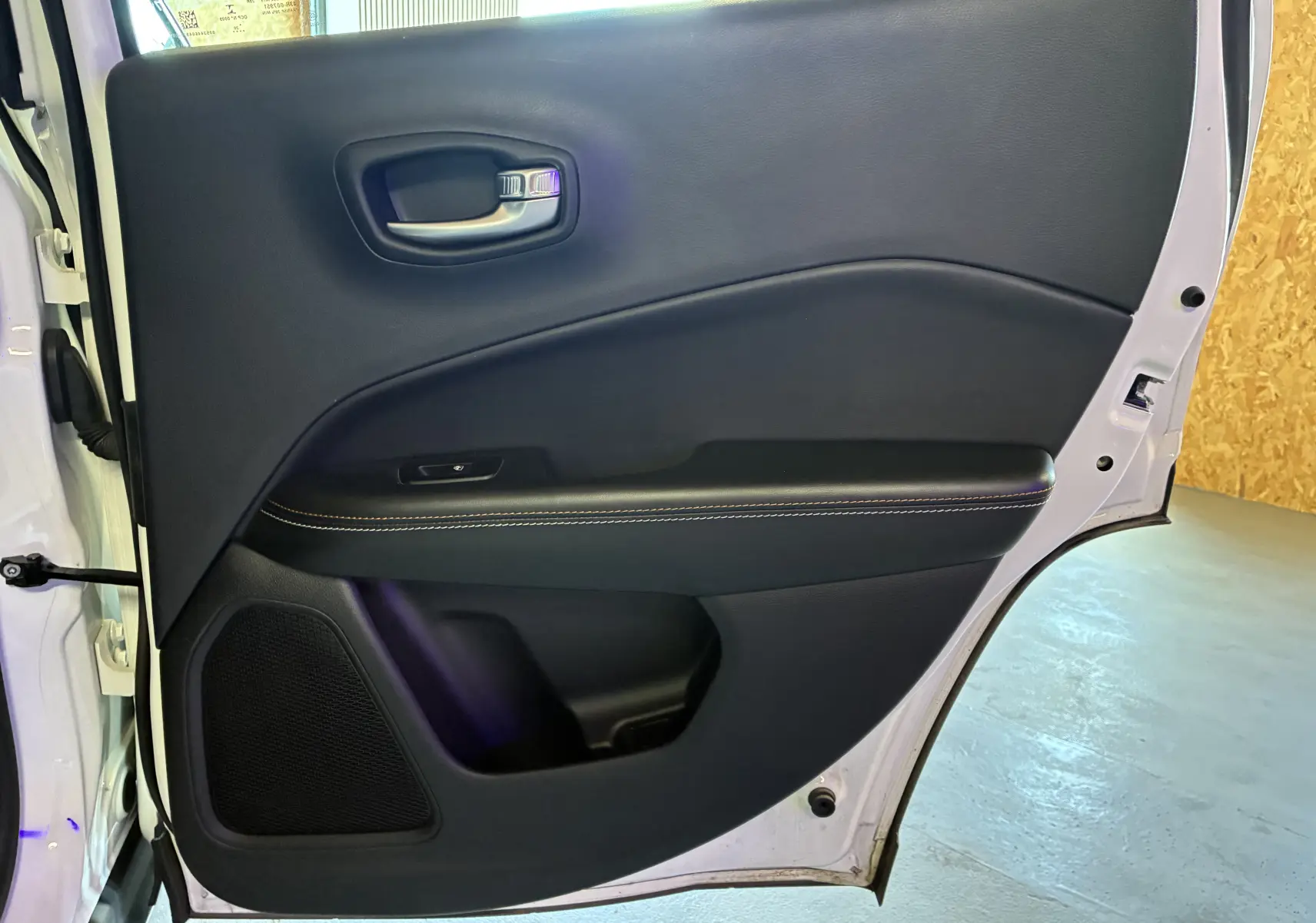 Vue rapprochée de la porte arrière droite ivoire du Jeep Compass 2021 avec garniture noire et surpiqûres contrastées.