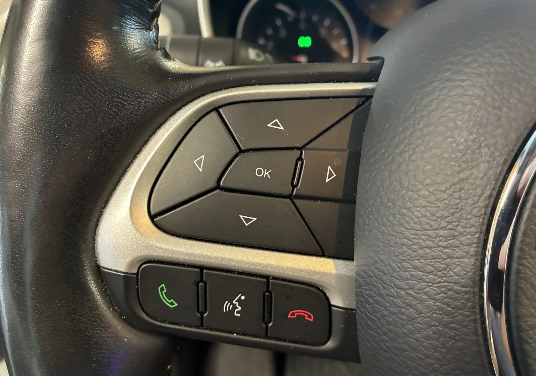 Gros plan sur les commandes noires multifonctions à gauche du volant cuir du Jeep Compass ivoire 2021.