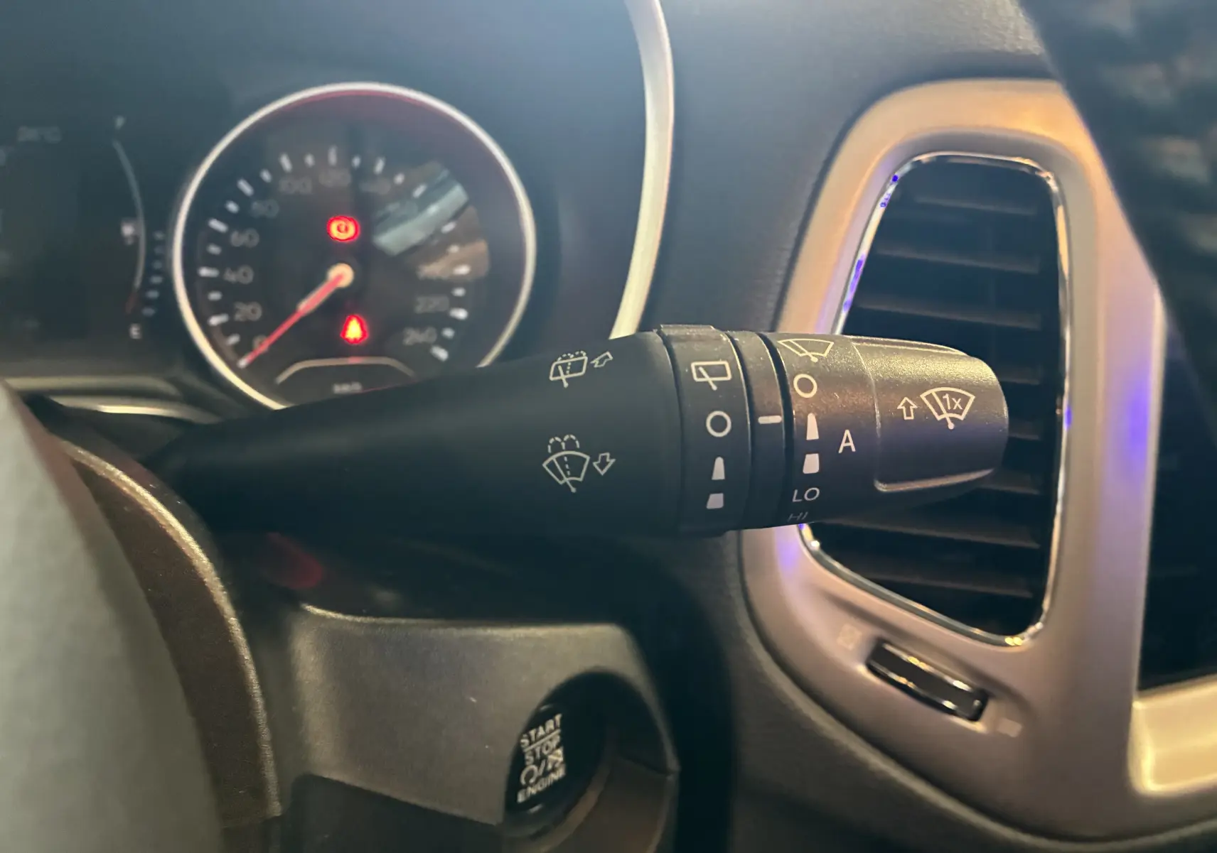 Gros plan sur la commande des essuie-glaces à gauche du volant dans l’habitacle noir du Jeep Compass ivoire 2021.