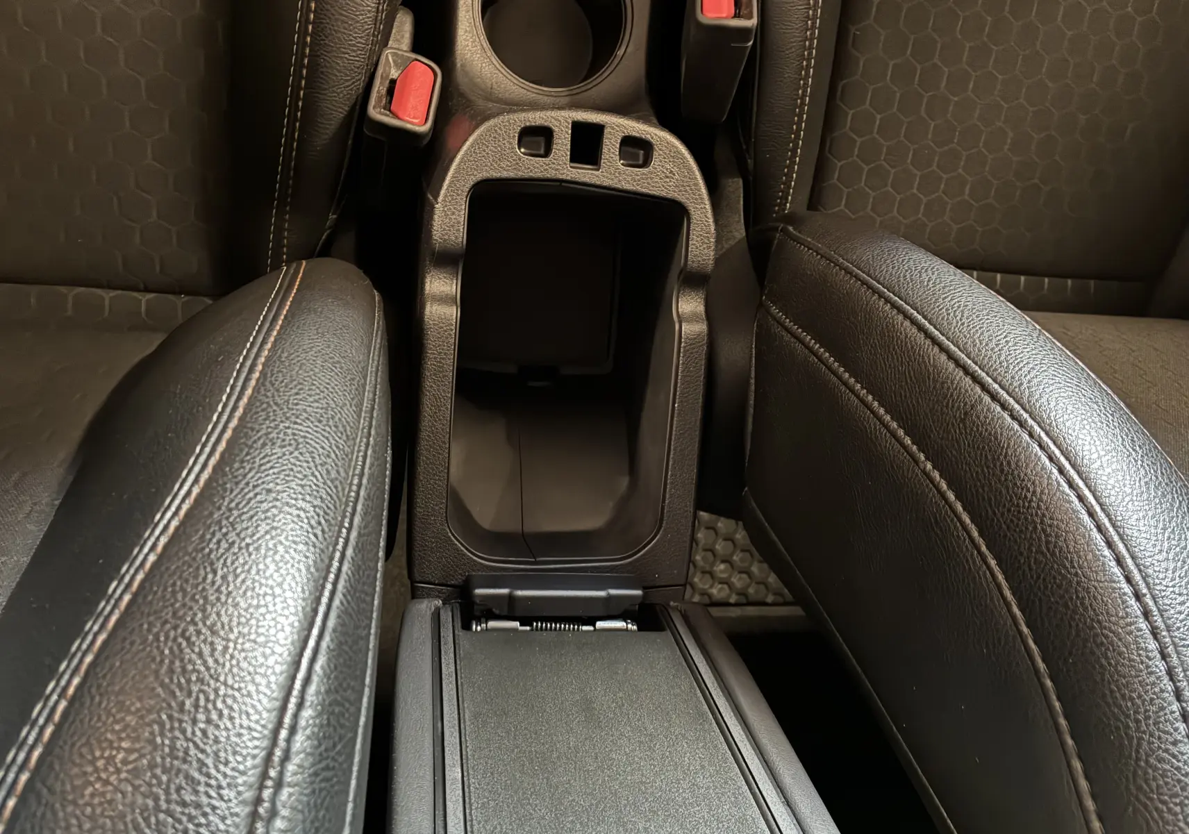Gros plan sur l'accoudoir central avant en cuir noir avec rangement ouvert du Jeep Compass Longitude ivoire.