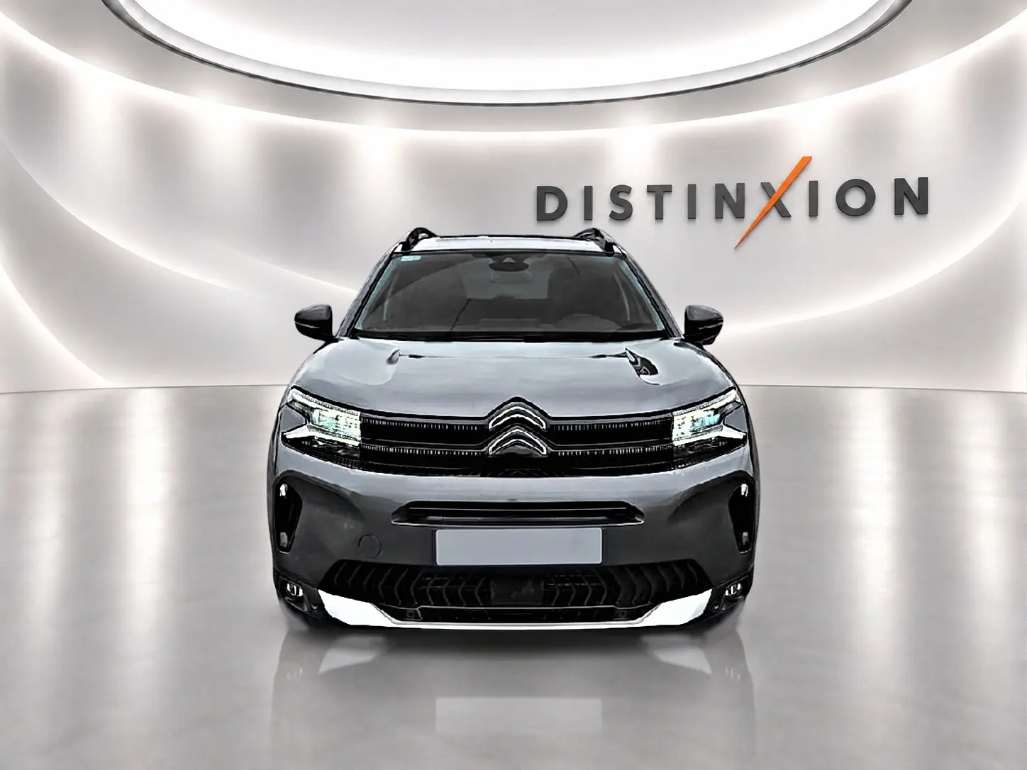 Citroën C5 Aircross gris vue de face dans un showroom avec éclairage moderne et logo Distinxion en arrière-plan.