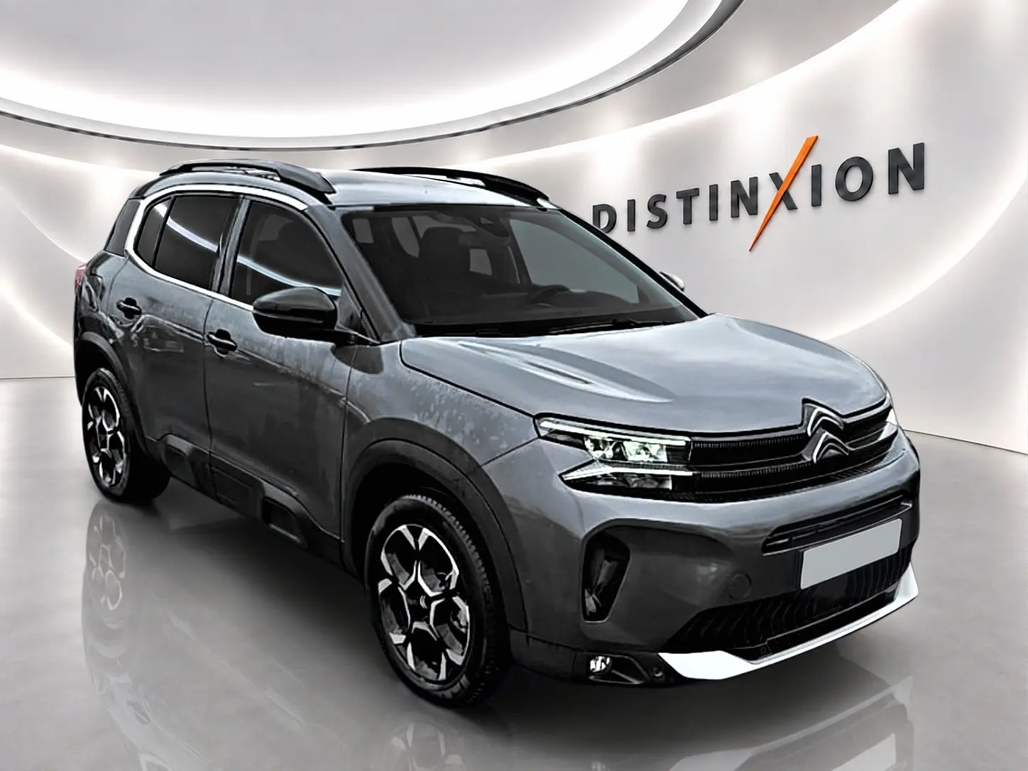Citroën C5 Aircross gris 3/4 avant droit en showroom avec barres de toit et jantes alu distinctives.