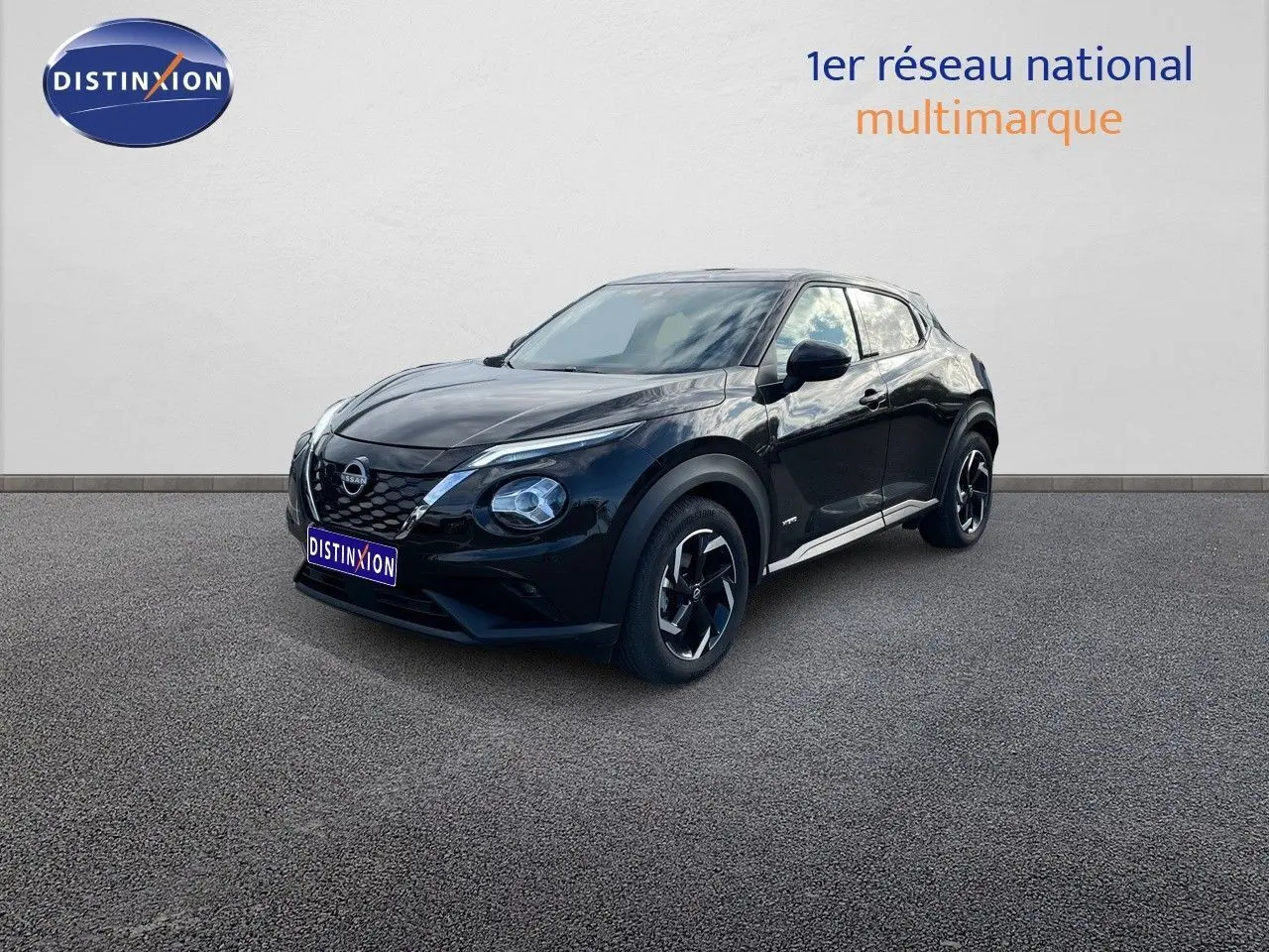 Nissan Juke 2024 noir métal en 3/4 avant droit, avec jantes bi-ton et calandre distinctive V-Motion.