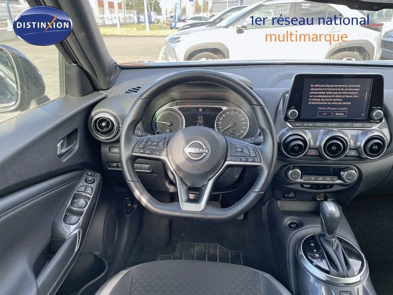 Vue intérieure du tableau de bord et volant noir du Nissan Juke 1.6 HEV 2024 avec écran tactile et boîte automatique.