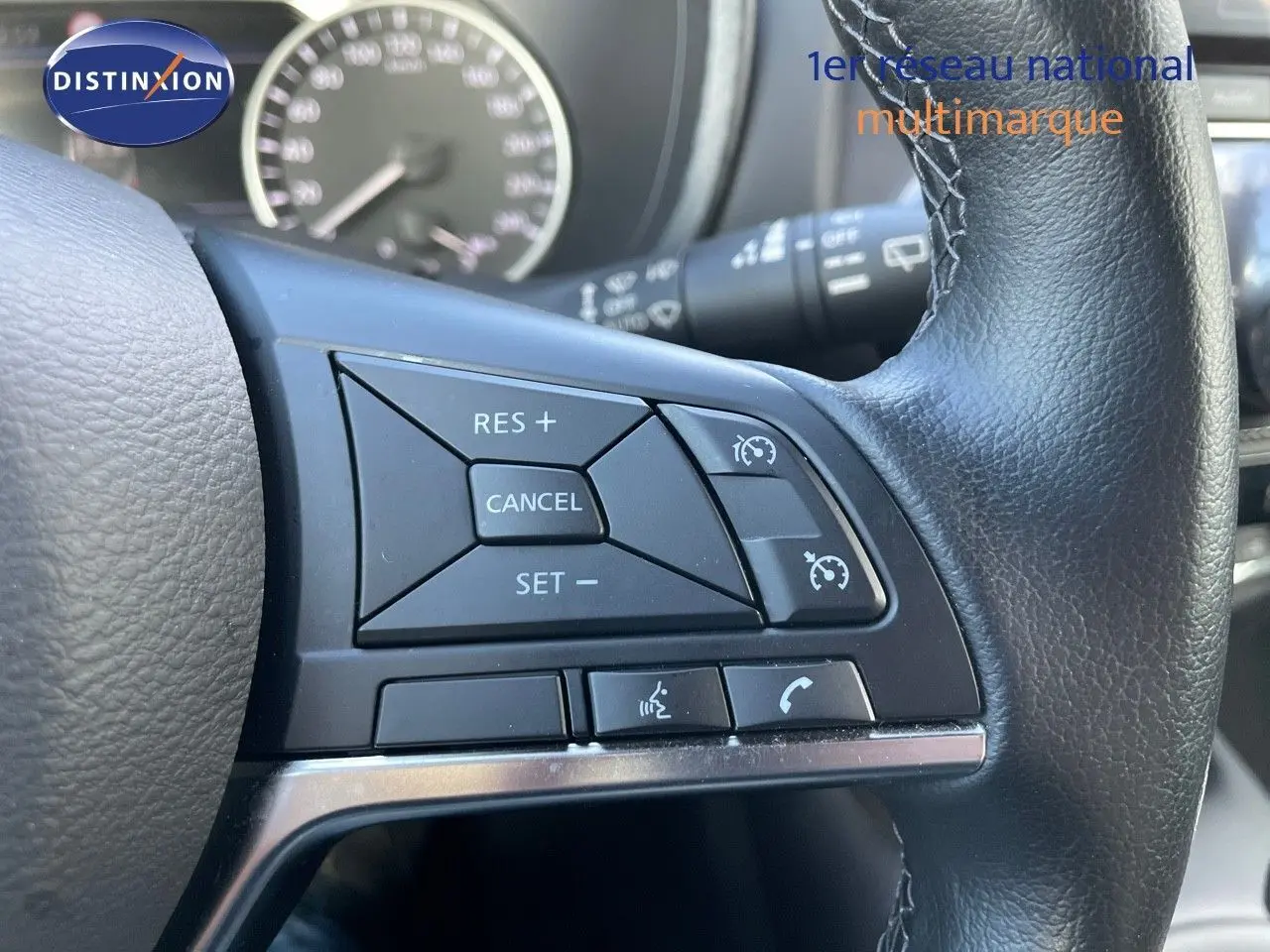 Gros plan sur les commandes de régulateur de vitesse au volant cuir noir du Nissan Juke 2024 hybride.
