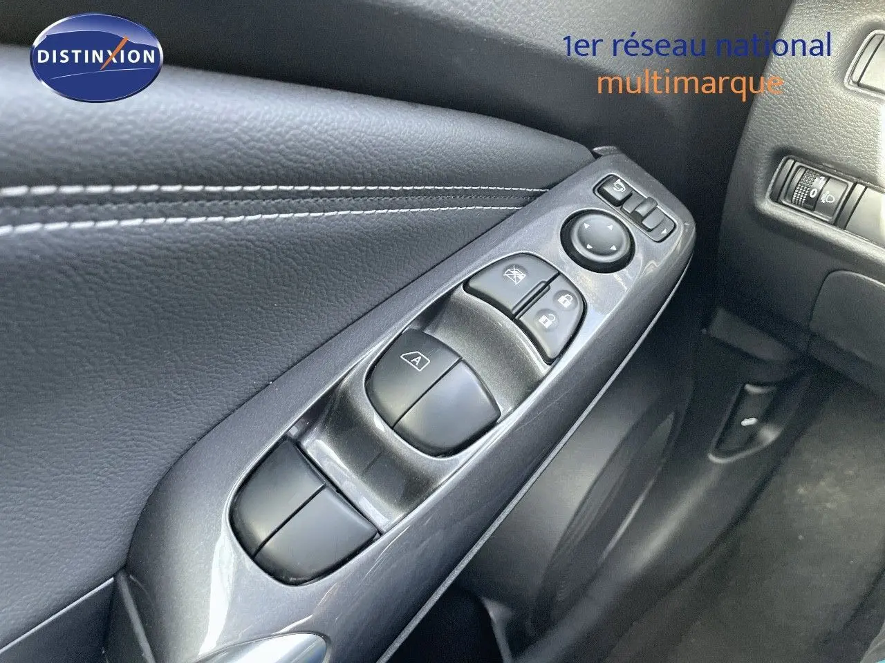Gros plan sur les commandes de lève-vitres et rétroviseurs côté conducteur du Nissan Juke noir métal 2024.