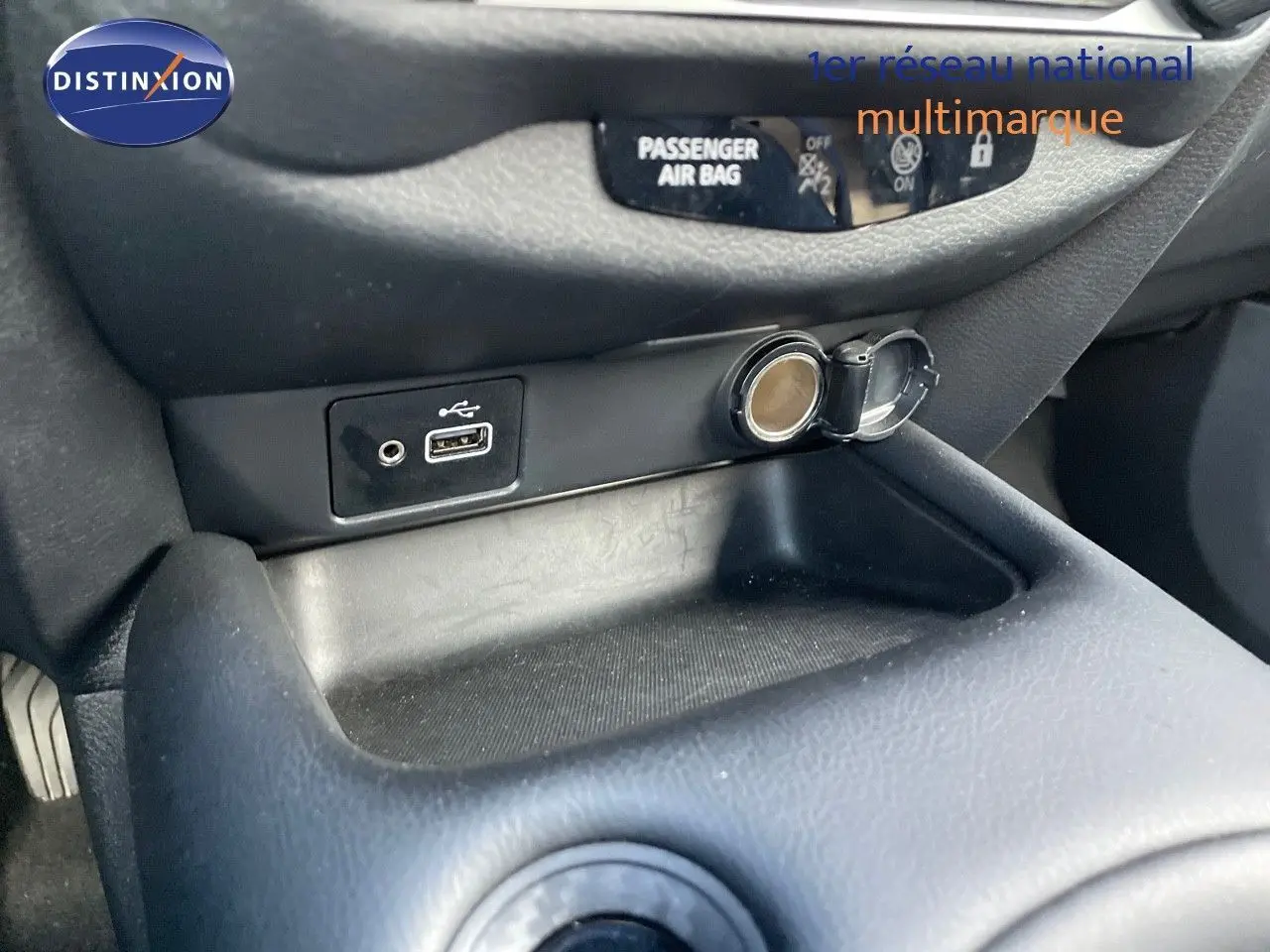 Prise USB et allume-cigare en gros plan sur la console centrale du Nissan Juke noir métal 2024.