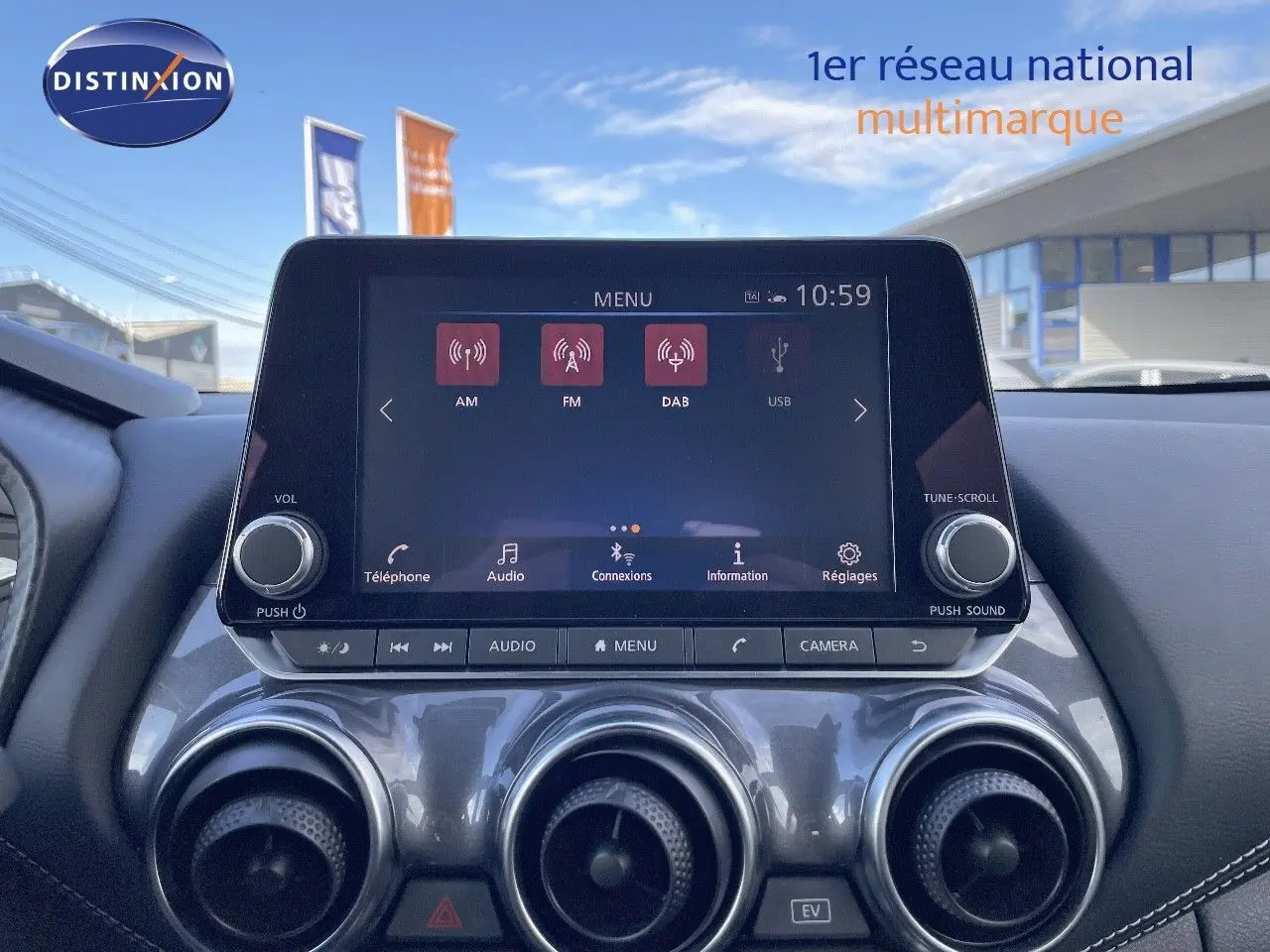 Vue rapprochée de la console centrale du Nissan Juke 2024 noir métal, avec écran tactile et commandes d’aération circulaires.