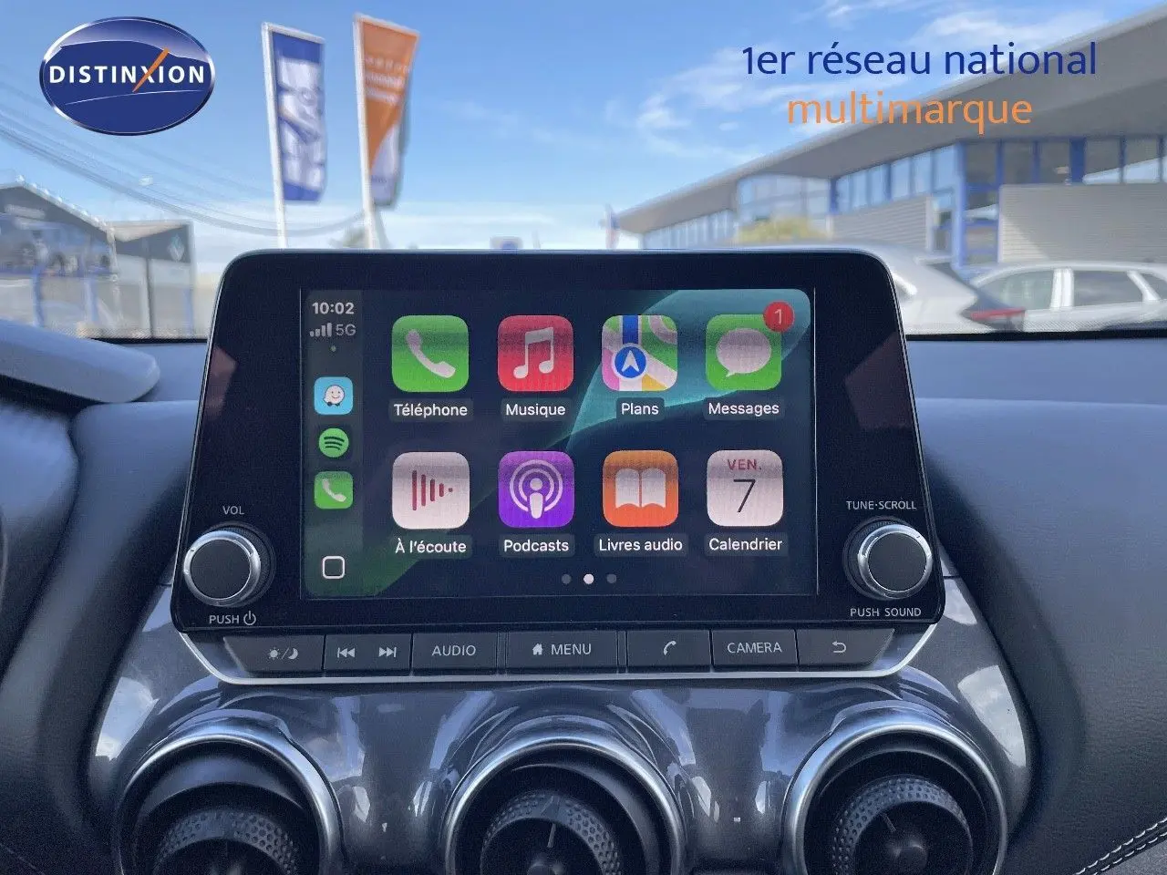 Écran tactile central allumé avec interface Apple CarPlay dans le tableau de bord du Nissan Juke noir métal 2024.