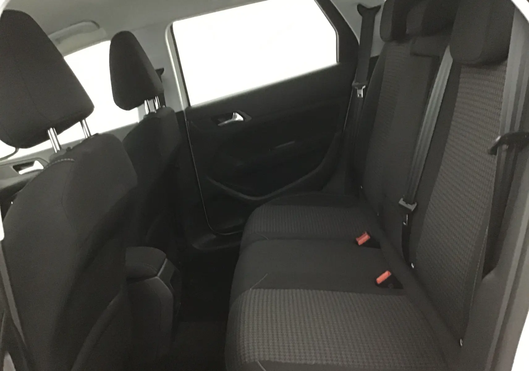 Vue intérieure côté droit des sièges arrière noirs à motifs de la Peugeot 308 SW 2018 blanche.