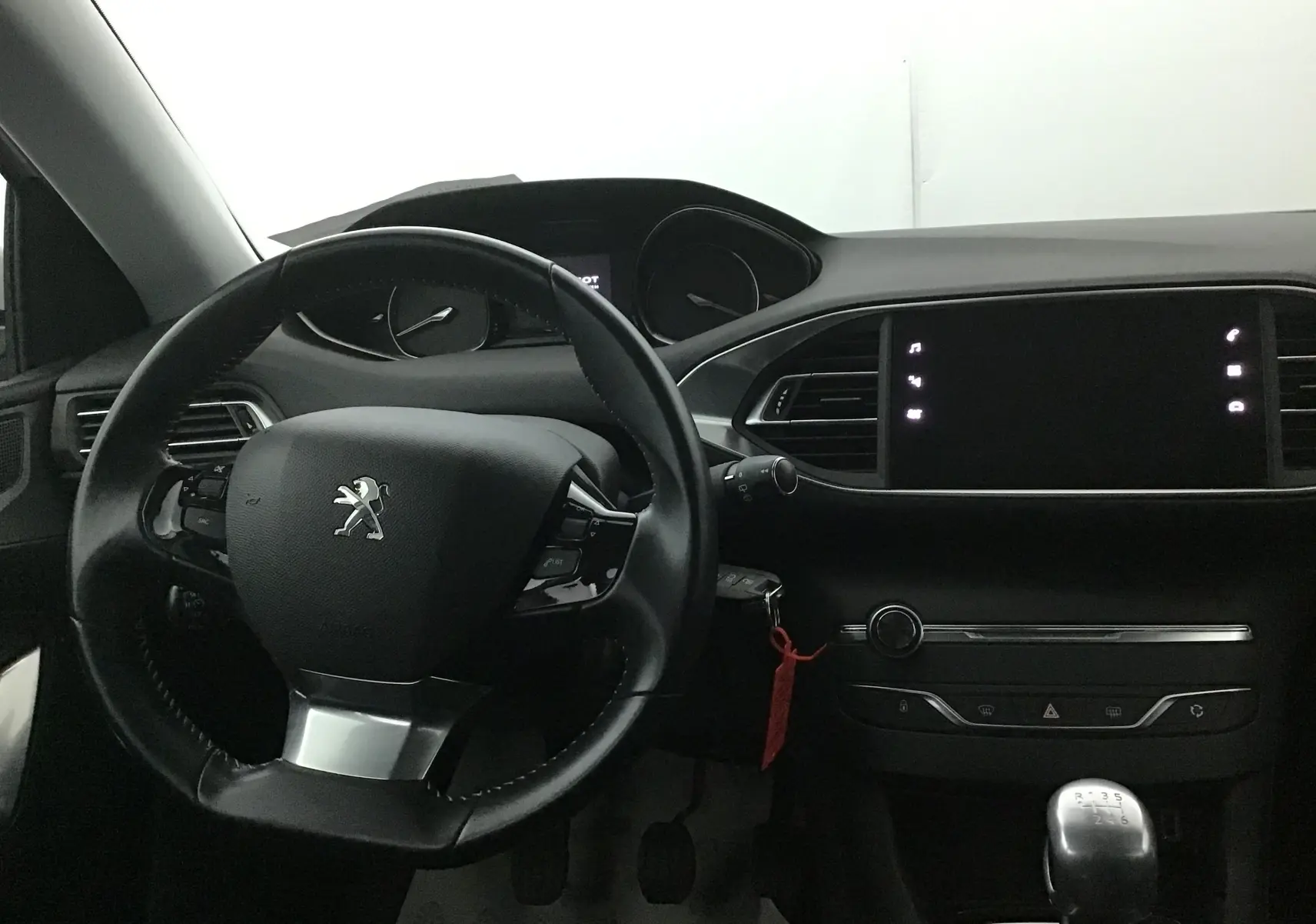 Intérieur noir de la Peugeot 308 SW 2018, vue du tableau de bord avec volant et levier de vitesse manuel.