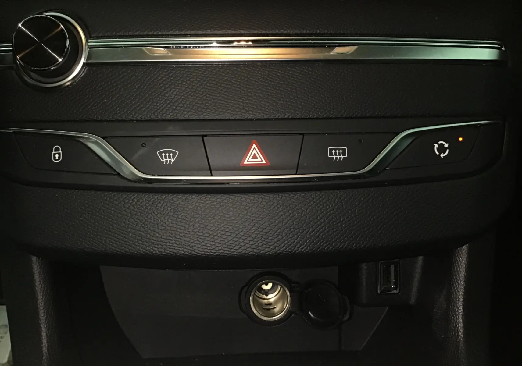 Vue rapprochée du tableau de bord noir du Peugeot 308 SW 2018, avec boutons de sécurité et prise allume-cigare ouverte.