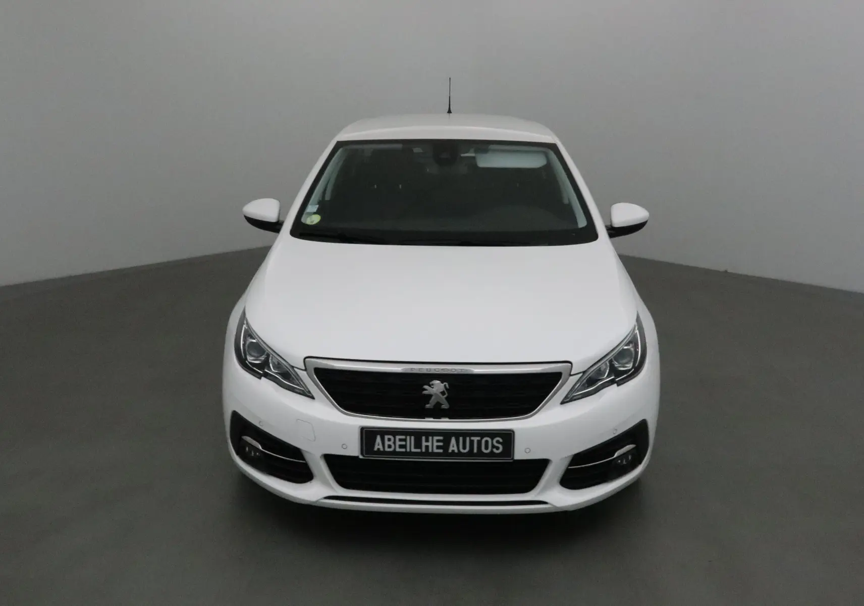 Vue frontale d'une Peugeot 308 SW blanche de 2018 avec calandre noire et logo lion visible.