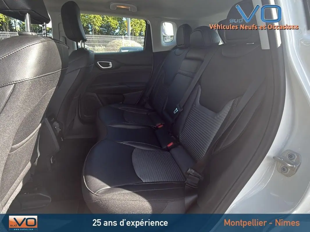 Vue intérieure arrière droite du Jeep Compass blanc 2024, sièges noirs en tissu et cuir avec ceinture de sécurité visible.