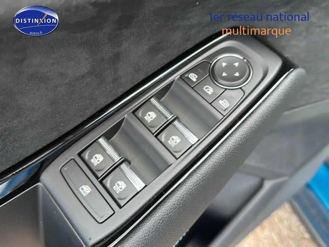 Gros plan sur les commandes des vitres électriques côté conducteur d’un Renault Austral bleu, avec finition intérieure noire.