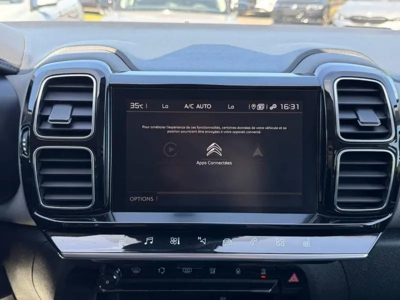 Vue rapprochée de l’écran tactile central noir du tableau de bord du Citroën C5 Aircross gris, avec aérateurs verticaux chromés.