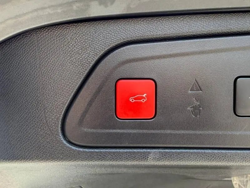Gros plan sur un bouton rouge d'ouverture du coffre dans l'habitacle d'un Citroën C5 Aircross gris 2020.