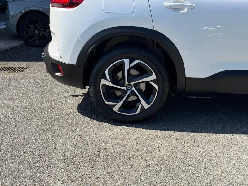 Gros plan sur la roue arrière droite d’un Citroën C5 Aircross gris avec jante alliage bicolore et passage de roue noir.
