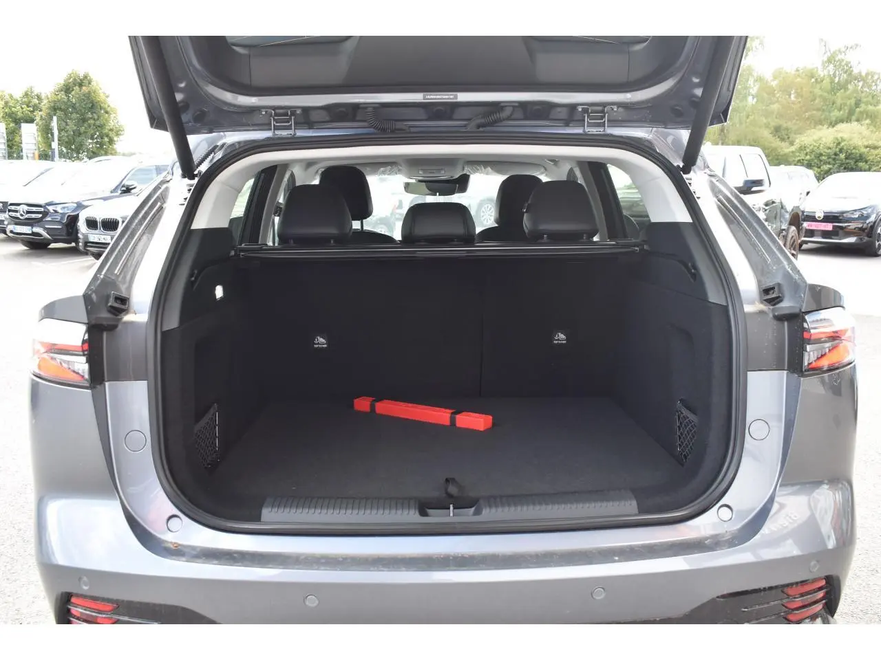 Coffre ouvert du MG MOTOR EHS 1.5 Hybrid+ gris 2026, vue arrière montrant l’espace de chargement et les sièges noirs.