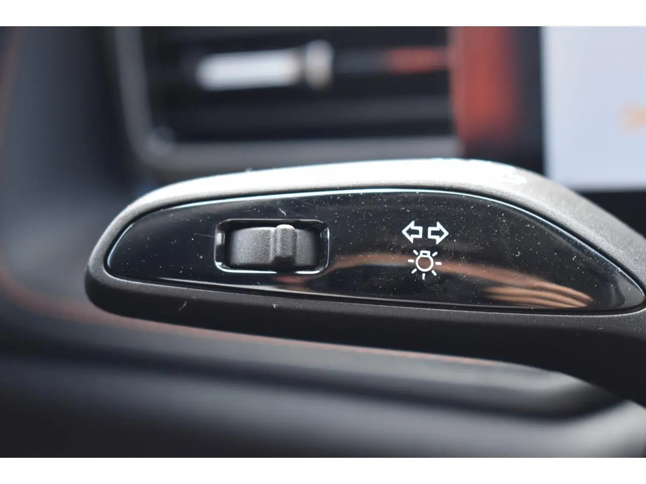 Gros plan sur le bouton de réglage des feux et clignotants dans l’habitacle du MG MOTOR EHS gris 2026.