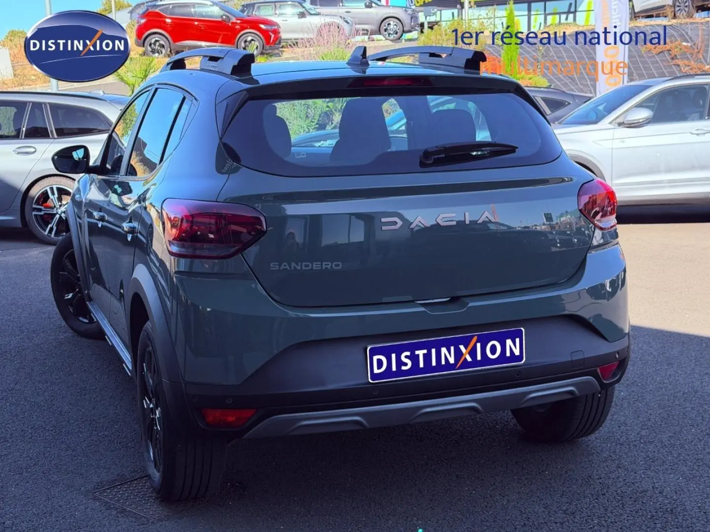 Vue 3/4 arrière d'une Dacia Sandero Stepway 2025 en kaki lichen avec barres de toit et jantes noires.