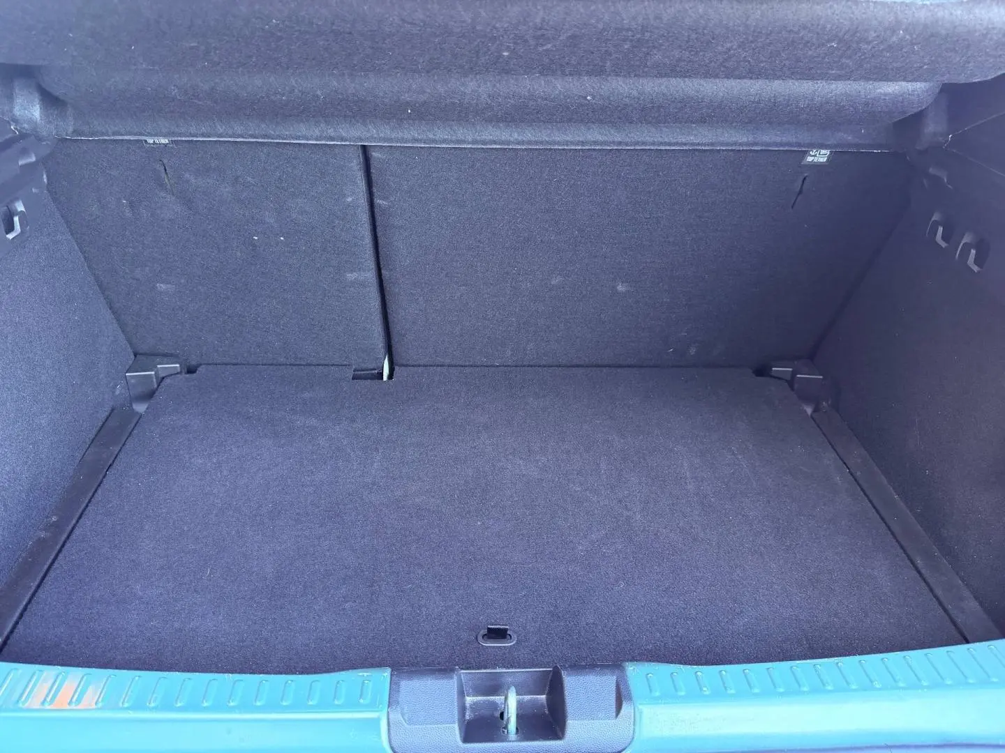 Coffre ouvert de Dacia Sandero Stepway 2025, vue intérieure, plancher plat et habillage noir uniforme.