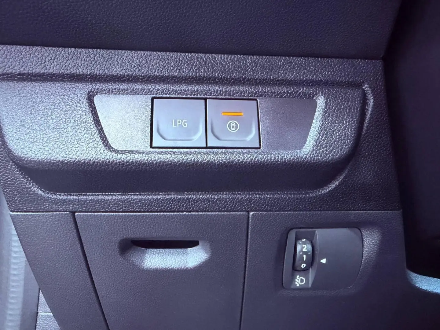 Gros plan sur les commandes intérieures noires du tableau de bord de la Dacia Sandero 2025, avec bouton LPG allumé.