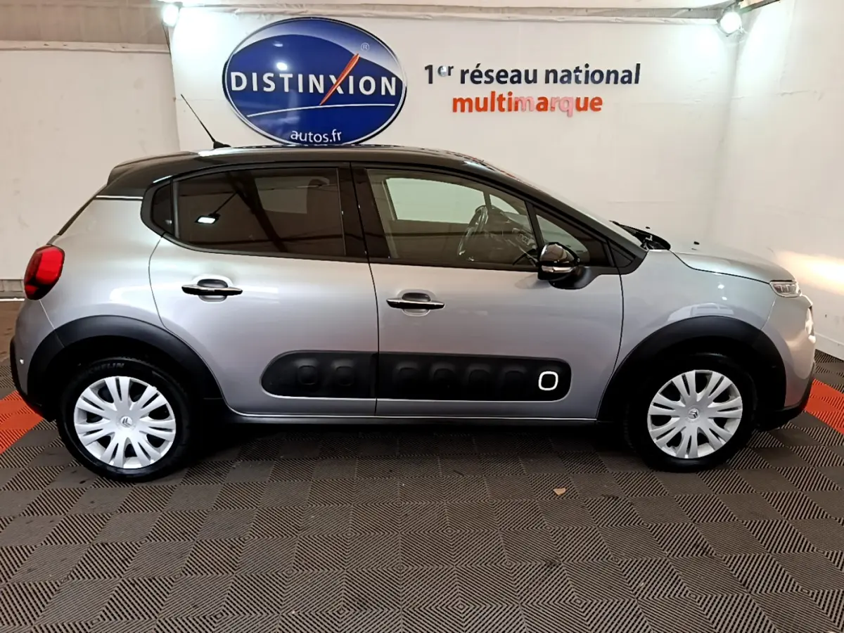 Citroën C3 gris clair vue profil côté gauche, avec protections latérales noires et jantes acier à enjoliveurs.
