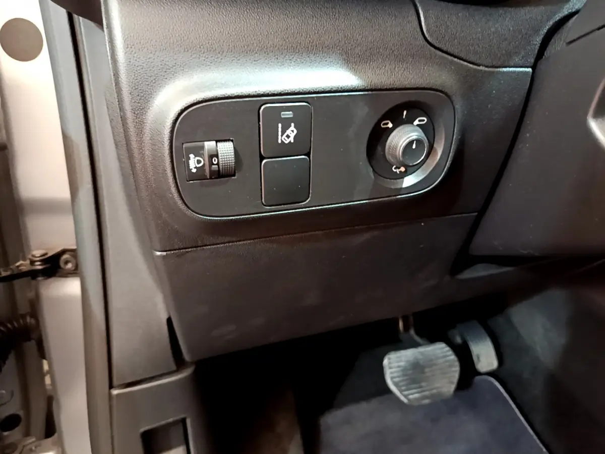Gros plan sur les commandes de réglage des phares et rétroviseurs côté conducteur d'une Citroën C3 gris clair 2019.