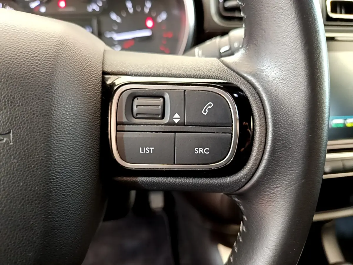 Gros plan sur les commandes gauche du volant cuir noir de la Citroën C3 2019, avec boutons audio et téléphone.