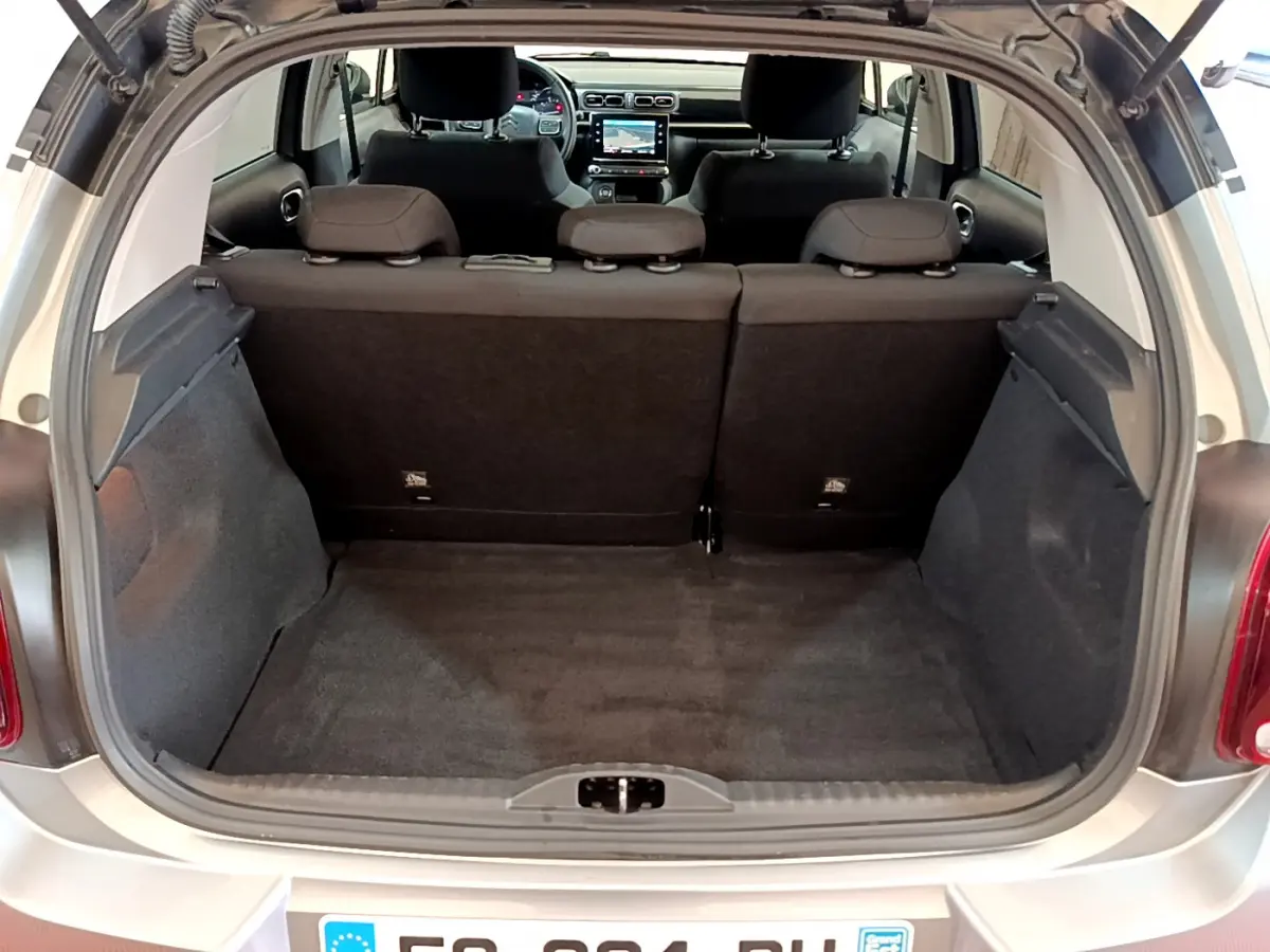 Coffre ouvert d'une Citroën C3 gris clair vue de l'arrière, montrant l'habitacle et l'écran tactile du tableau de bord.