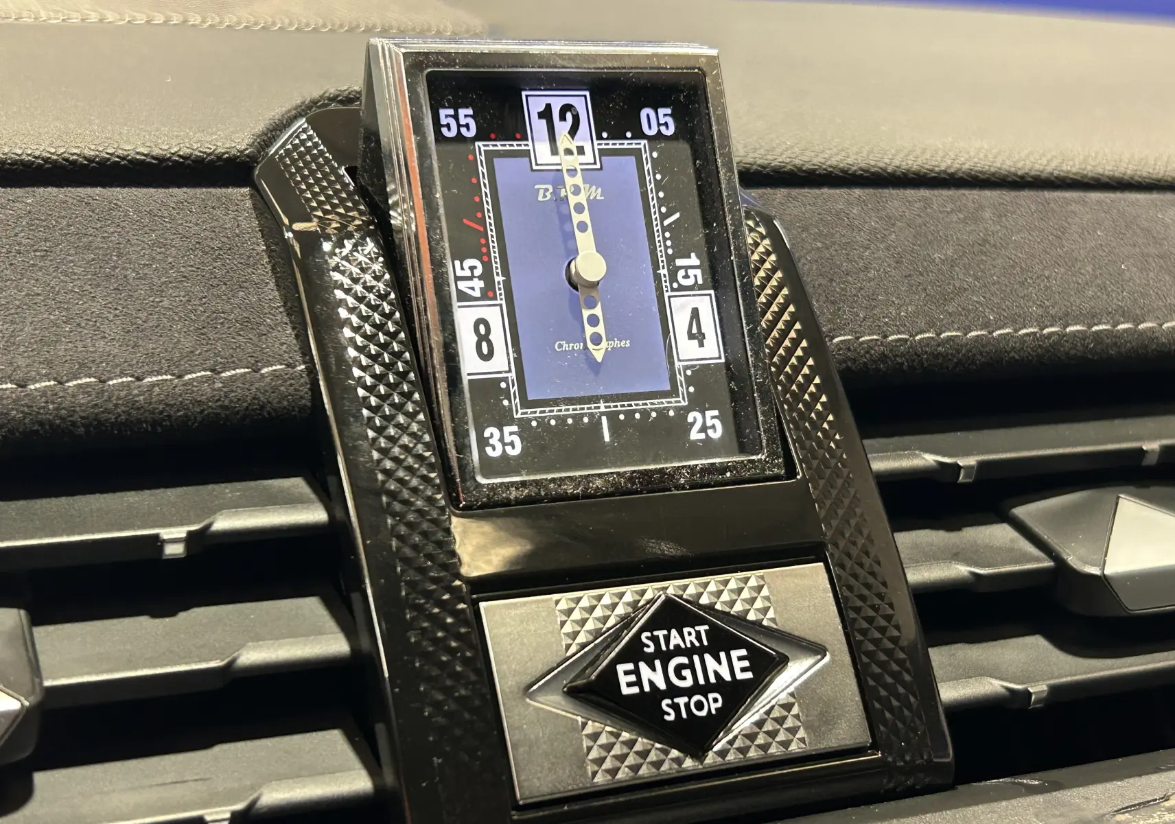 Gros plan sur l’horloge analogique et bouton start/stop du tableau de bord du DS7 gris titane 2024.